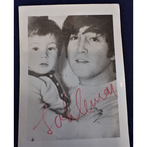 553 - A SIGNED BLACK AND WHITE PHOTOGRAPH OF JOHN LENNON holding a young boy, signed 'John Lennon' in red ... 