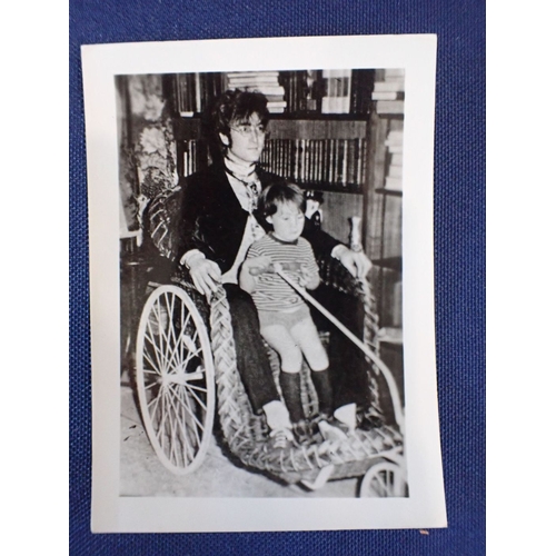 553 - A SIGNED BLACK AND WHITE PHOTOGRAPH OF JOHN LENNON holding a young boy, signed 'John Lennon' in red ... 