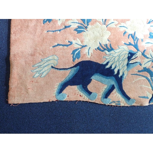 670 - RED CHINESE PICTORIAL RUG blue on pink ground depicting lions, unevenly cut at bottom edge, other da... 