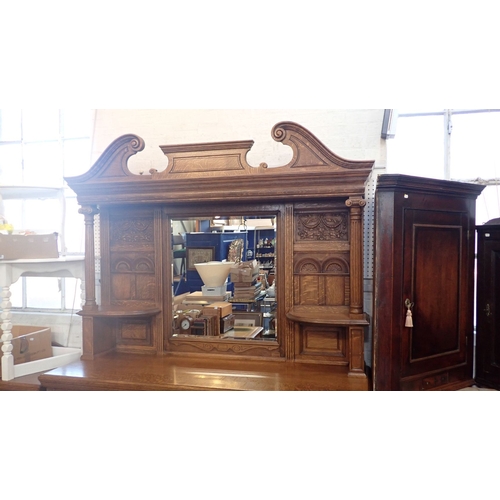 706 - A LATE VICTORIAN OAK BUFFET the mirrored superstructure with swan-neck pediment, over an arrangement... 