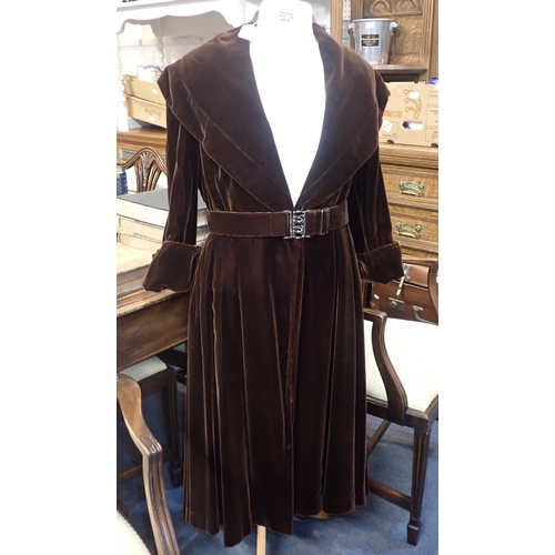 82 - A 1940S BROWN VELVET EVENING COAT with broad collar, buckled belt and quilted lining