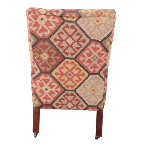 179 - A VICTORIAN KILIM COVERED ARMCHAIR 19th century, the square back over scrolling arms and a shaped se... 