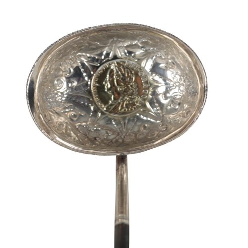 26 - A GEORGIAN WHITE METAL TODDY LADLE the embossed oval bowl inset with a George II 1758 gilt coin, wit... 