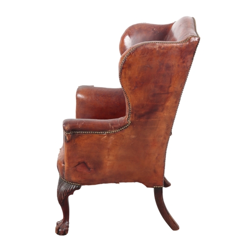 523 - A MAHOGANY WING ARMCHAIR late 19th / early 20th Century, upholstered in studded brown leather, on ca... 