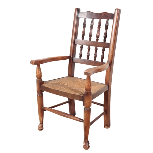 529 - A CHILD'S BEECHWOOD AND ELM ARMCHAIR early 20th Century, with two tier spindle back, rush seat, on t... 