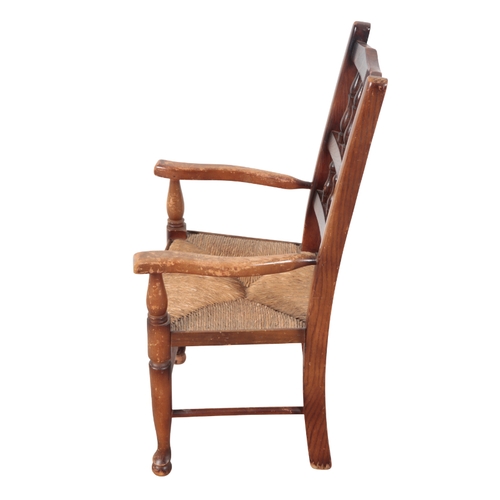 529 - A CHILD'S BEECHWOOD AND ELM ARMCHAIR early 20th Century, with two tier spindle back, rush seat, on t... 