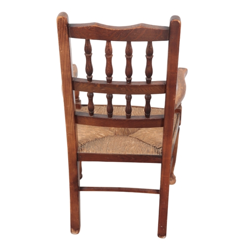 529 - A CHILD'S BEECHWOOD AND ELM ARMCHAIR early 20th Century, with two tier spindle back, rush seat, on t... 