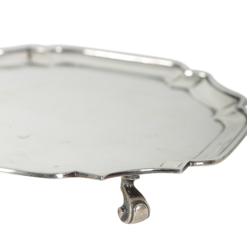 57 - A GEORGE V SILVER WAITER of 18th Century style, with pie-crust rim, on scroll feet, 20.5cm square, 1... 