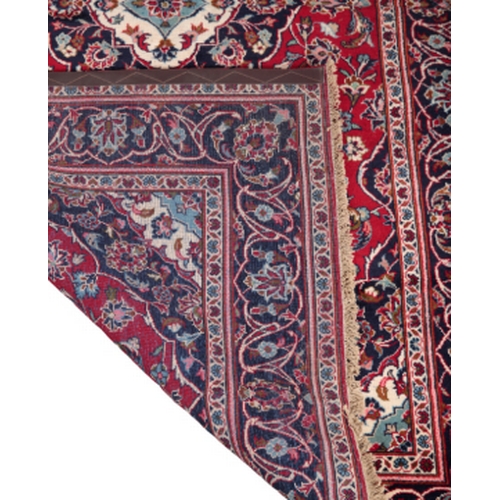 592 - A CENTRAL PERSIAN KASHAN RUG the central medallion on a rich red ground populated with stylised flor... 