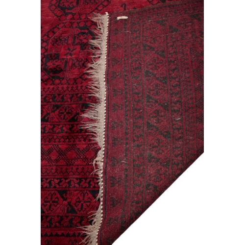 595 - AN ANTIQUE AFGAN MAIN CARPET woven in black with three rows of six guls and filler motifs on a cochi... 