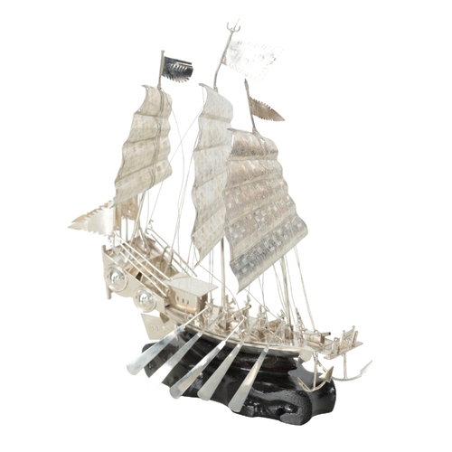 125 - A CHINESE WHITE METAL MODEL OF A THREE MASTED JUNK on carved ebonised plinth, 37cm high