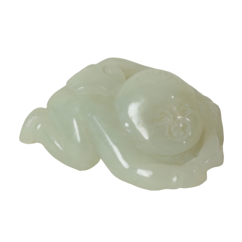 127 - A CHINESE PALE CELADON JADE CARVING OF A BOY lying on his front, holding a vine to his back, 5.5cm l... 