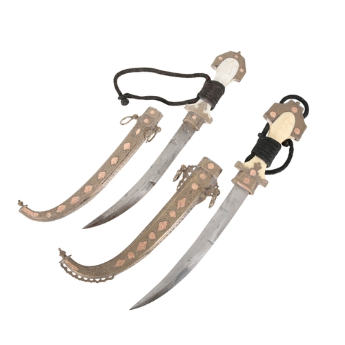 166 - A PAIR OF MOROCCAN JAMBIYAS 20th Century, the 23cm steel blades with plastic, white and gilt metal h... 