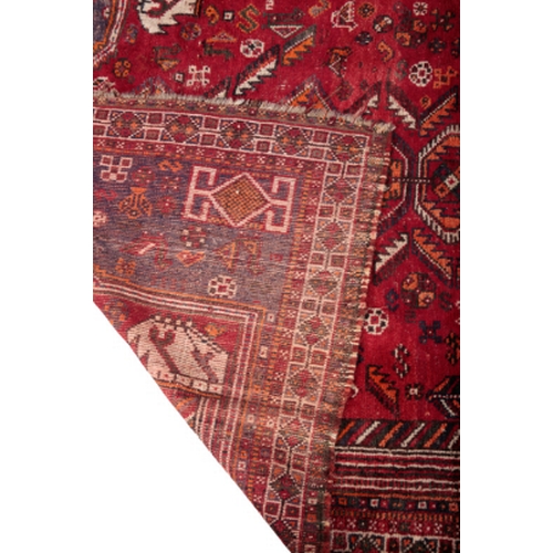 391 - A SHIRAZ RUG woven in red, orange and off white with nine lozenge pole medallion and filler motifs o... 