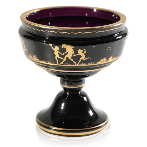 584 - A SMALL BLACK AMETHYST PEDESTAL VASE WITH OVERLAID GILT DECORATION OF CHILDREN FROLICKING c. 1900, p... 