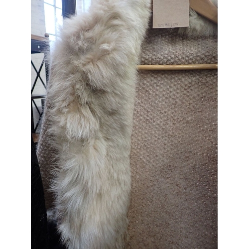 200 - A CREAM KNITTED CAPE EDGED WITH FUR together with one other black cape (2)