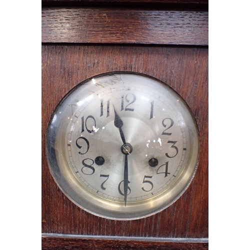 226 - A 1930S OAK WALL CLOCK striking on a gong, with silvered dial and glazed door