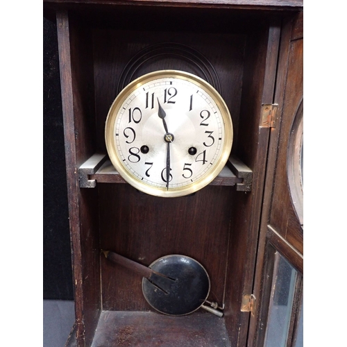 226 - A 1930S OAK WALL CLOCK striking on a gong, with silvered dial and glazed door