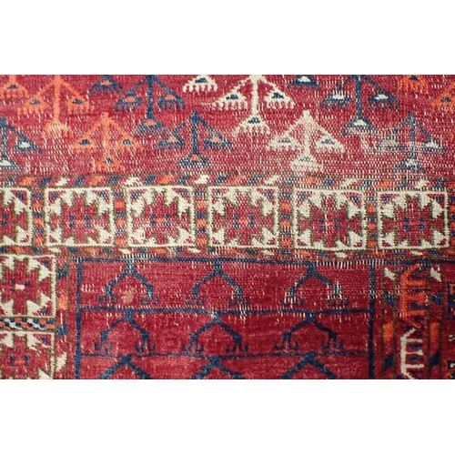 571 - AN ANTIQUE TURKMEN ENNSI woven in muted colours and white with traditional geometric pattern on a co... 