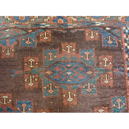 578 - AN ANTIQUE TURKMEN RUG woven in blue, red and white with endless gul repeat on a brown ground, withi... 