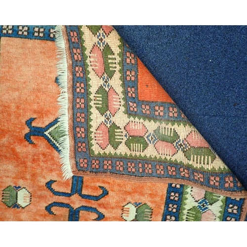 579 - A TURKISH RUG woven in blue and green with twin hooked lozenge medallions on a red ground within geo... 