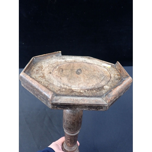 595 - AN OAK TRIPOD CANDLE STAND with octagonal top (some mouldings missing, one leg loose, other damage)