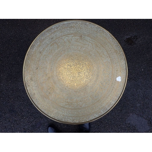 621 - A NEAR EASTER BRASS TOP CIRCULAR OCCASIONAL TABLE on reeded hardwood folding stand