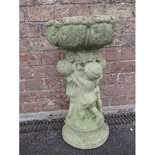 6 - A RECONSTITUTED STONE BIRD BATH the leaf-moulded basin supported by putti 55cm high