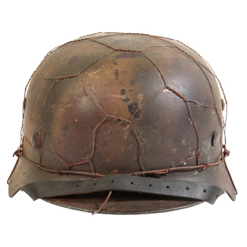 509 - A WWII GERMAN HELMET with a single decal, M43 field brown camouflage with metal-covered netting and ... 