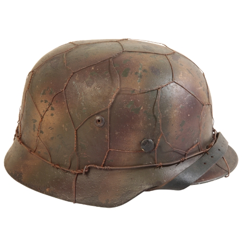 509 - A WWII GERMAN HELMET with a single decal, M43 field brown camouflage with metal-covered netting and ... 