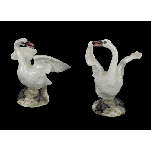 102 - AN OPPOSING PAIR OF 19TH CENTURY MEISSEN SWANS modelled with wings outstretched on rocky bases, each... 