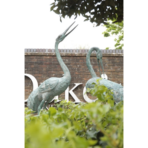 19 - A PAIR OF IMPRESSIVE PAINTED METAL CRANES with verdigris effect, cast naturalistically in opposing s... 