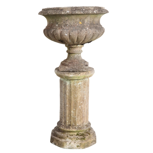 33 - A PAIR OF RECONSTITUTED STONE URNS the shaped and gadrooned bowls on turned plinth bases, together w... 