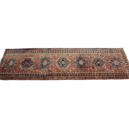 349 - A PERSIAN RUNNER 20th century, with central alternating geometric medallions, on a brick red ground,... 