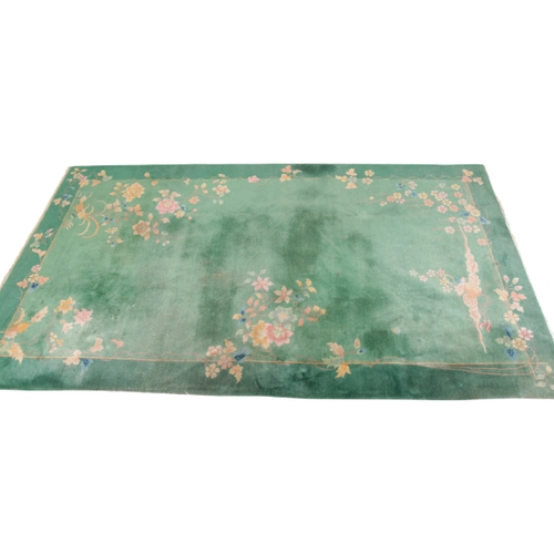 351 - A CHINESE CARPET woven in colours with floral sprays on an open green ground, 390cm x 140cm