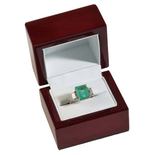 29 - AN EMERALD AND DIAMOND RING with step-cut diamond shoulders, the central emerald calculated weight a... 