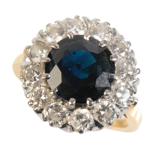 35 - A SAPPHIRE AND DIAMOND CLUSTER RING the round-cut sapphire, within a border of twelve brilliant-cut ... 