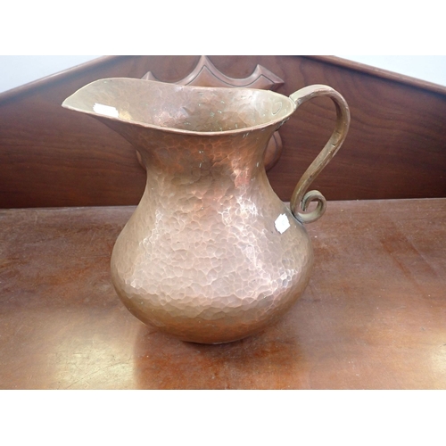 16 - A HAMMERED ARTS AND CRAFTS STYLE COPPER JUG 27.5cms height