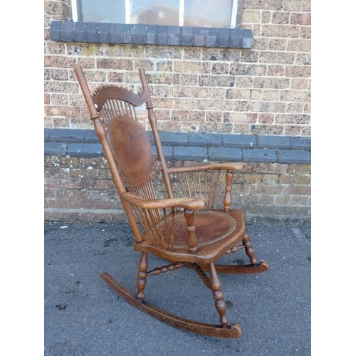 677 - AN OAK ROCKING CHAIR, WITH PRESSED LEATHER SEAT and shaped back with spindles, probably American