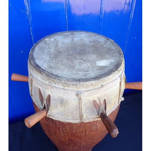 126 - A TRIBAL HARDWOOD DRUM the skin held with long pegs 53cm high