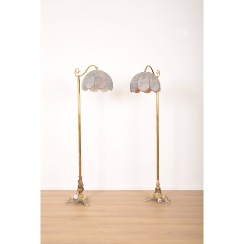 56 - A PAIR OF BRASS STANDARD LAMPS 19th century, the electric fitments and fabric shades held on scrolle... 