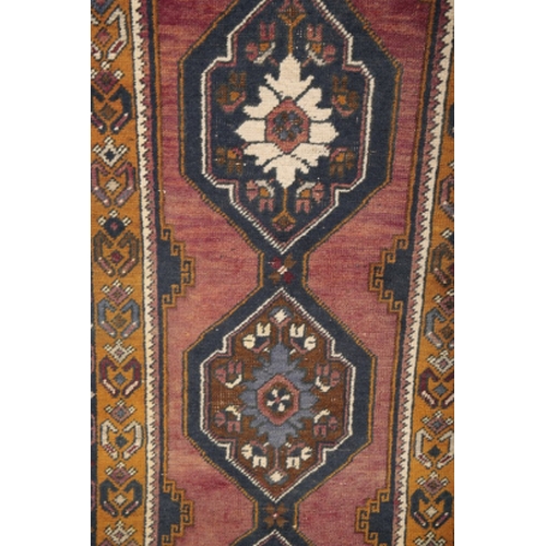 65 - A TURKISH RUNNER 20th century, the brick red ground with repeating medallions, within contrasting bo... 