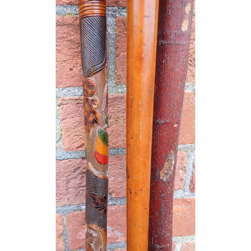 144 - A CARVED ASIAN WALKING STICK carved and painted with a brass topped walking pole, a carved baton and... 