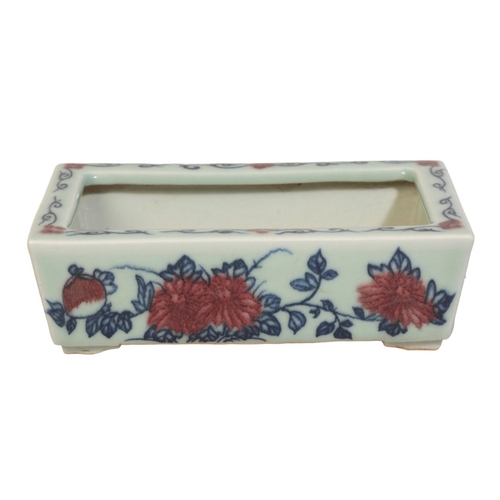 49 - A CHINESE CELADON RECTANGULAR JARDINIERE

decorated in underglaze blue and iron red with sprays of f... 