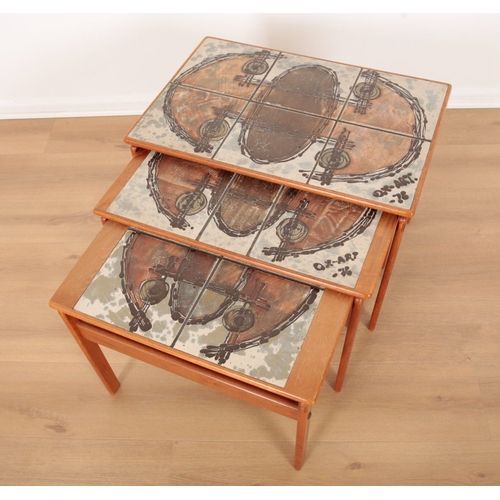 560 - A NEST OF THREE TEAK TABLES

mid 20th century, each with hand painted tile inset tops, the largest 4... 