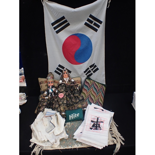 111 - TWO EXOTIC PUPPETS with a collection of linen, two cushions, a hanging tapestry and a Korean flag