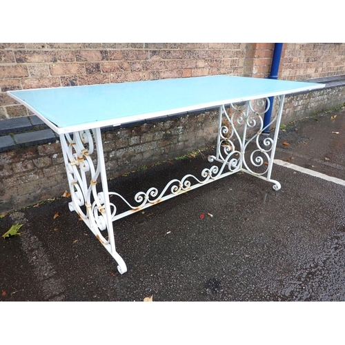 13 - A WROUGHT-IRON FRAMED GARDEN DINING TABLE the scrolling base painted white, with blue glass top