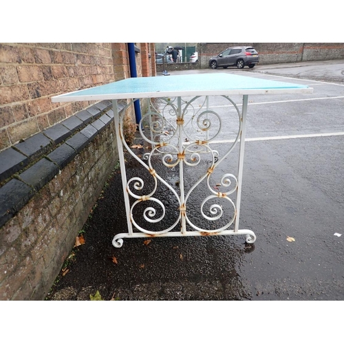 13 - A WROUGHT-IRON FRAMED GARDEN DINING TABLE the scrolling base painted white, with blue glass top