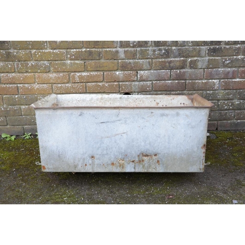 3 - A GALVANISED METAL TROUGH of tapered rectangular section, 44cm high x 94cm long x 69cm wide