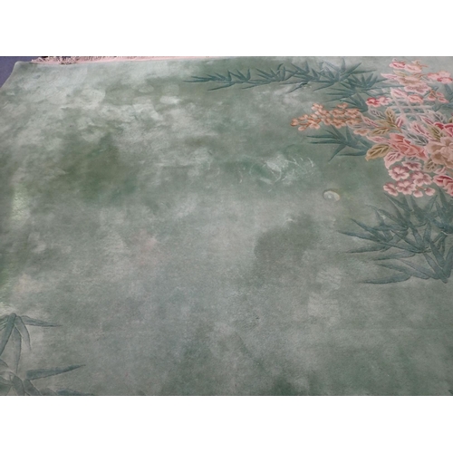 865 - LARGE GREEN CHINESE RUG with bamboo and camellias decoration, 303cm x 430cm plus fringes